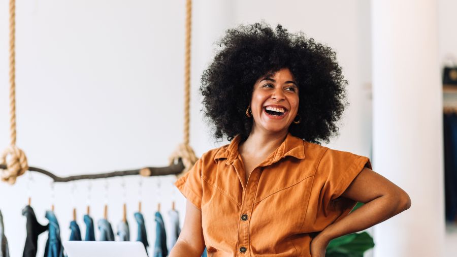 Cover image for The New Consumer Reality showing a smiling woman in a retail environment with clothing racks in the background.