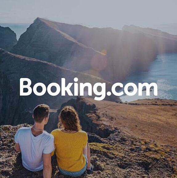 Photo of two people sitting on a cliff overlooking a coastal landscape